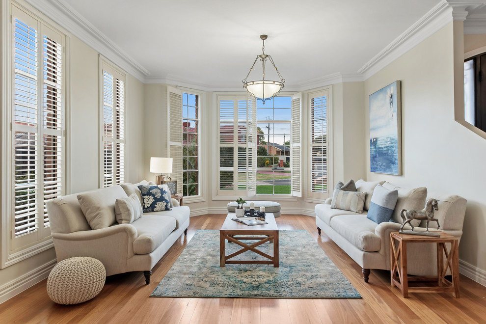 Traditional open concept living room in Melbourne with medium hardwood floors, brown floor and beige walls.