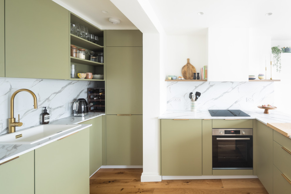 This is an example of a medium sized contemporary u-shaped open plan kitchen in London with an integrated sink, white splashback, marble splashback and no island.