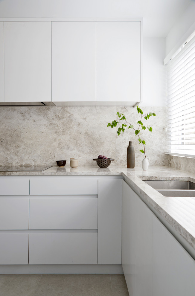 Small world-inspired u-shaped enclosed kitchen in London with a built-in sink, flat-panel cabinets, white cabinets, marble worktops, beige splashback, marble splashback, black appliances, porcelain flooring, no island, grey floors and beige worktops.
