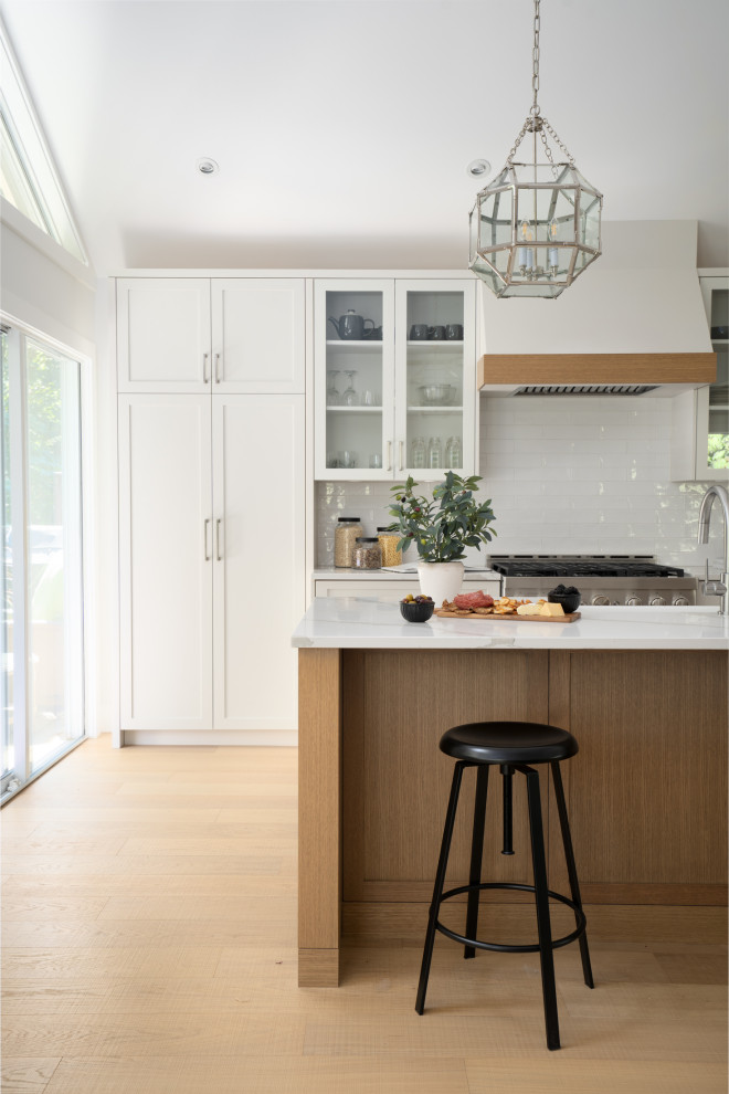 Inspiration for a transitional brown floor eat-in kitchen remodel in Vancouver with a drop-in sink, shaker cabinets, white backsplash, stainless steel appliances, an island and white countertops