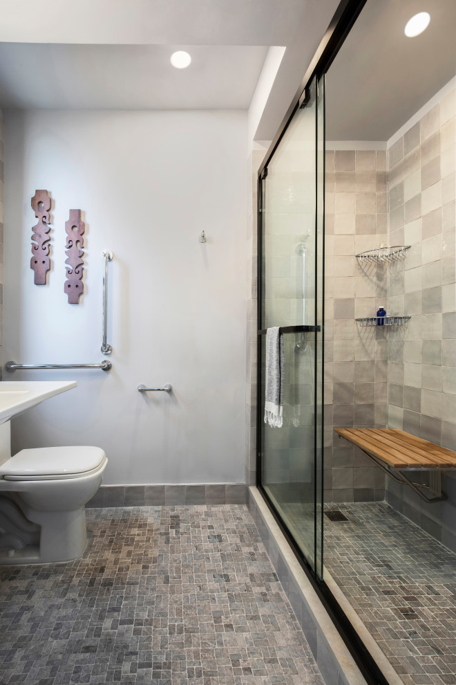 Идея дизайна: главная ванная комната среднего размера в современном стиле с открытым душем, унитазом-моноблоком, серой плиткой, каменной плиткой, серыми стенами, полом из керамической плитки, накладной раковиной, серым полом, душем с раздвижными дверями, сиденьем для душа, тумбой под одну раковину и подвесной тумбой