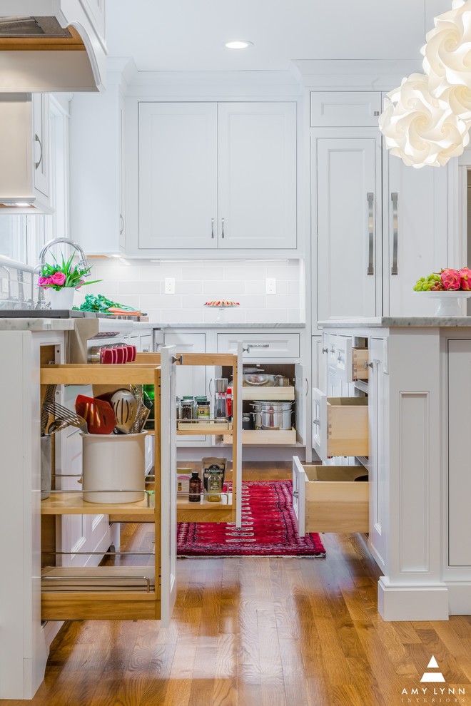 Example of a mid-sized transitional l-shaped medium tone wood floor and red floor eat-in kitchen design in Boston with an undermount sink, beaded inset cabinets, white cabinets, marble countertops, gray backsplash, porcelain backsplash, paneled appliances, an island and yellow countertops