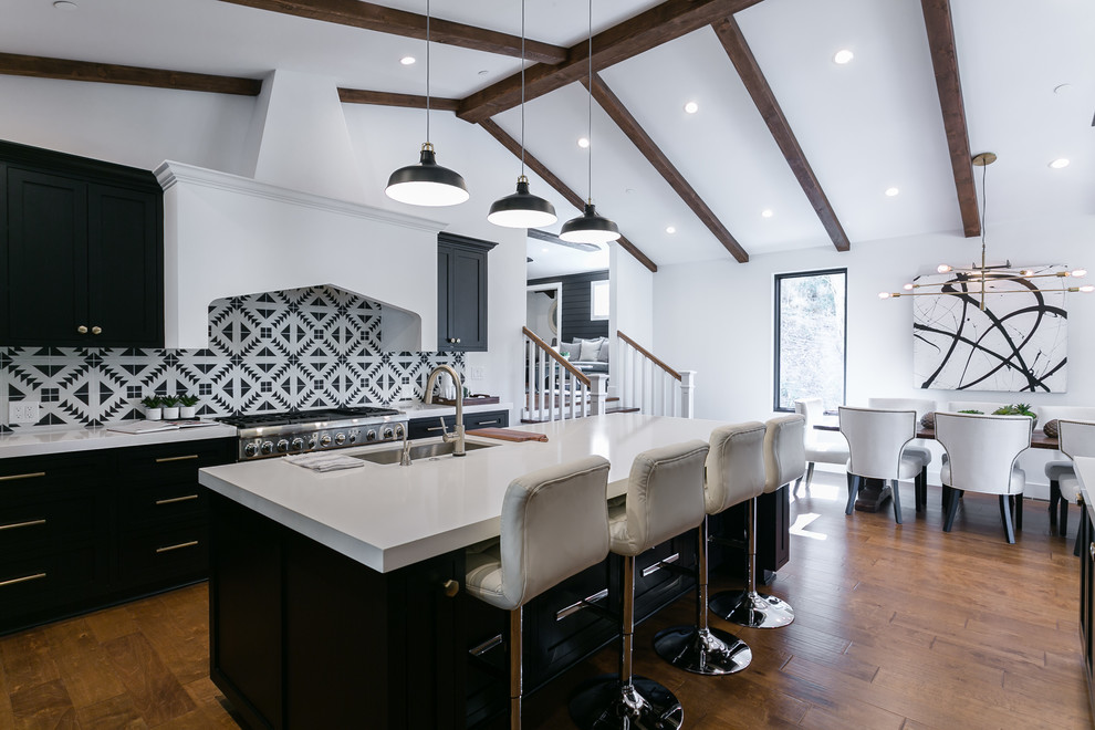 Enclosed kitchen - mid-sized transitional u-shaped medium tone wood floor and brown floor enclosed kitchen idea in Los Angeles with an undermount sink, shaker cabinets, black cabinets, solid surface countertops, stainless steel appliances and an island