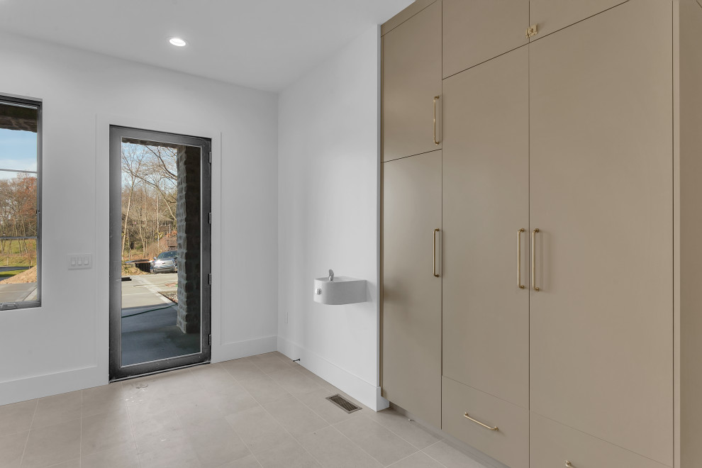 Example of a large transitional ceramic tile and beige floor mudroom design with white walls and a glass front door