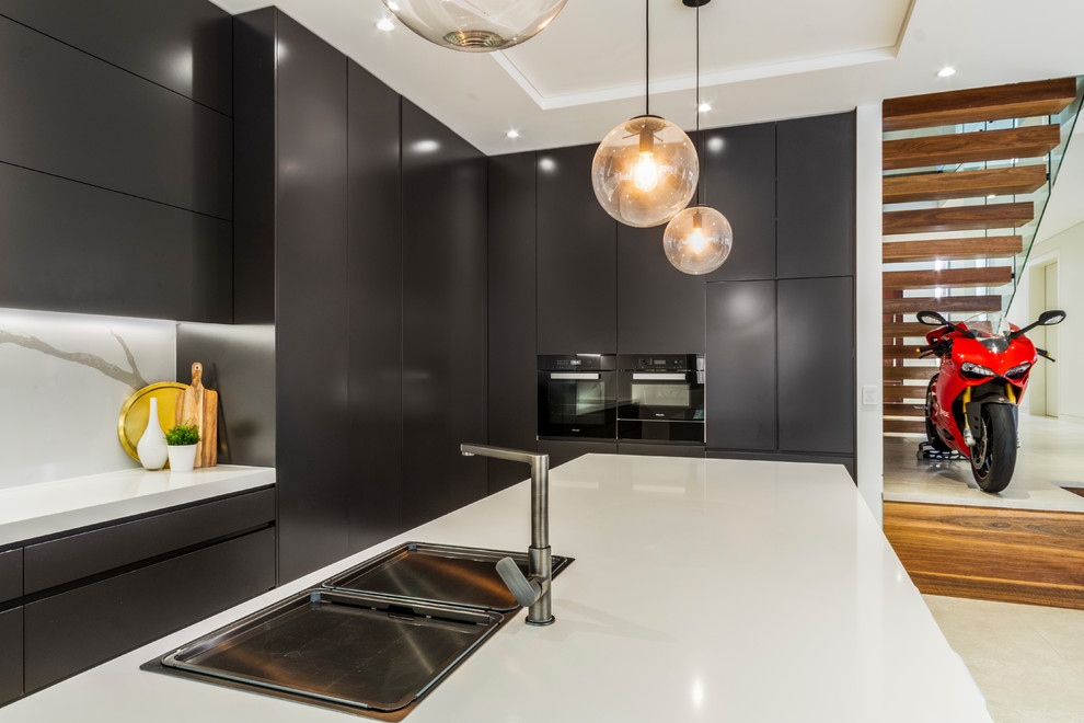 Design ideas for a large contemporary galley kitchen pantry in Sydney with a drop-in sink, flat-panel cabinets, black cabinets, quartz benchtops, white splashback, stone slab splashback, stainless steel appliances, ceramic floors, with island, beige floor and white benchtop.