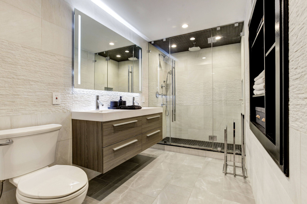 Large minimalist master beige tile and porcelain tile porcelain tile, gray floor and double-sink alcove shower photo in New York with flat-panel cabinets, brown cabinets, a two-piece toilet, beige walls, a wall-mount sink, solid surface countertops, a hinged shower door, white countertops, a niche and a floating vanity