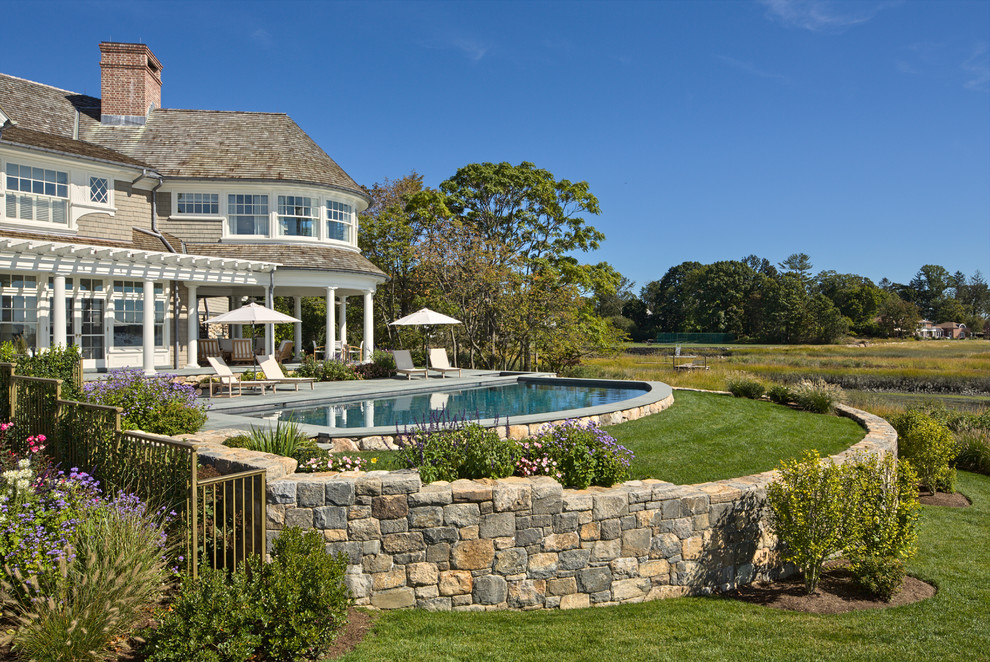 This is an example of a large traditional backyard custom-shaped lap pool in New York with decking and a hot tub.