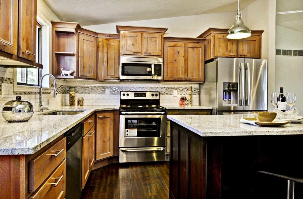 Open concept kitchen - mid-sized transitional l-shaped dark wood floor open concept kitchen idea in Boise with an undermount sink, shaker cabinets, medium tone wood cabinets, granite countertops, white backsplash, ceramic backsplash, stainless steel appliances and an island