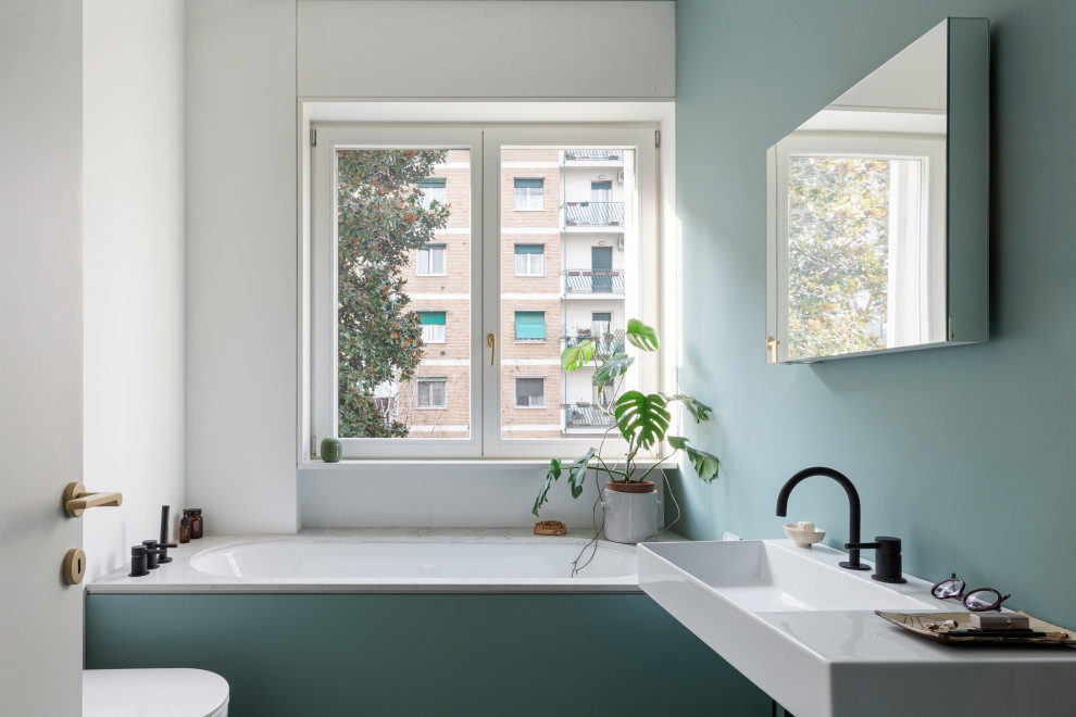 Mid-sized contemporary 3/4 bathroom in Milan with an undermount tub, a curbless shower, a wall-mount toilet, green tile, green walls, concrete floors, engineered quartz benchtops, green floor, a hinged shower door, white benchtops and a single vanity.