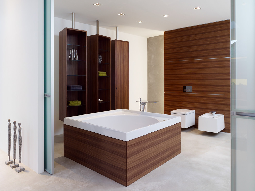 Photo of a large contemporary bathroom in Dusseldorf with open cabinets, dark wood cabinets, a freestanding tub, a bidet, white walls and concrete floors.