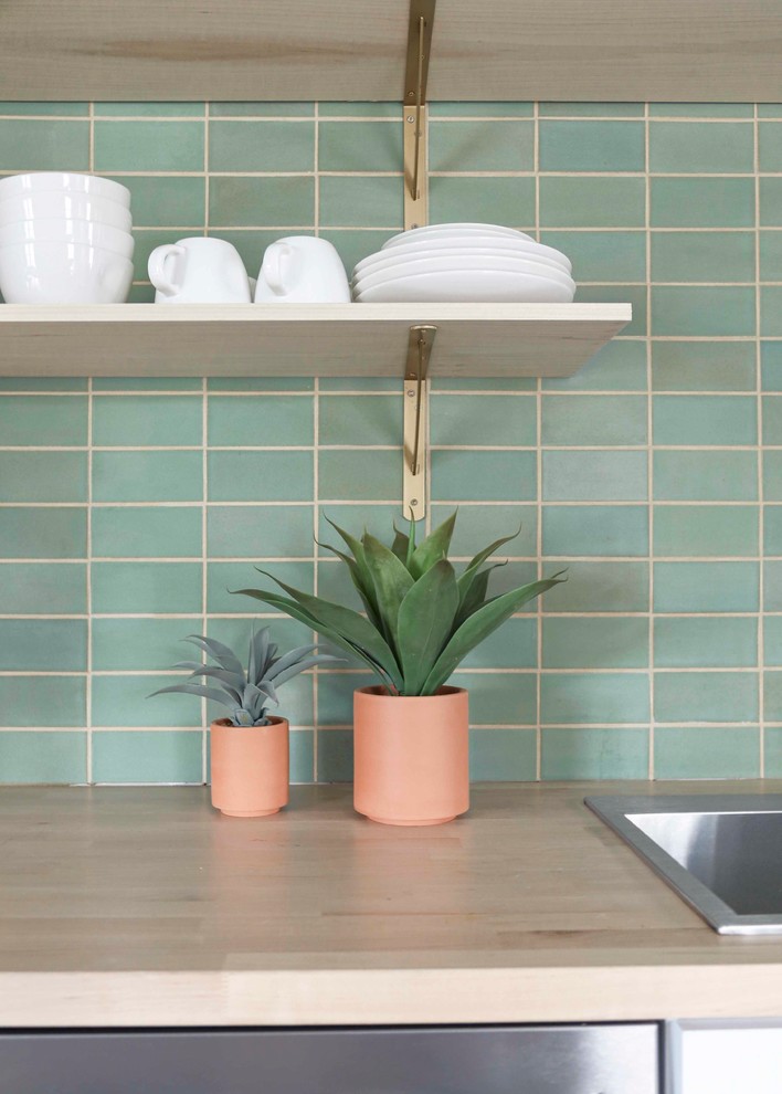 Small transitional l-shaped light wood floor and brown floor open concept kitchen photo in Minneapolis with a drop-in sink, flat-panel cabinets, white cabinets, wood countertops, green backsplash, ceramic backsplash, stainless steel appliances, no island and brown countertops