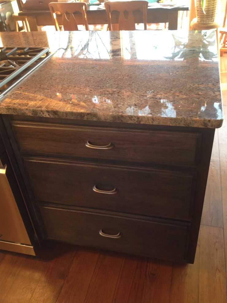 Kitchen - small rustic kitchen idea with a double-bowl sink, dark wood cabinets, granite countertops, stainless steel appliances and an island