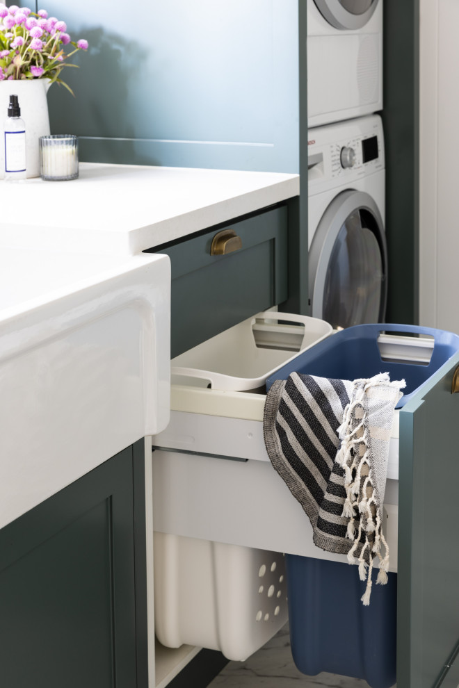 Laundry room in Sydney with a farmhouse sink, shaker cabinets, green cabinets, white splashback, shiplap splashback, marble floors and a stacked washer and dryer.
