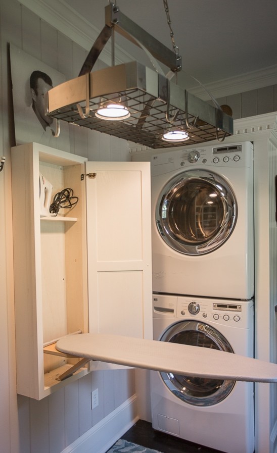This is an example of a small transitional u-shaped utility room in Other with a farmhouse sink, recessed-panel cabinets, white cabinets, wood benchtops, beige walls, painted wood floors and a stacked washer and dryer.