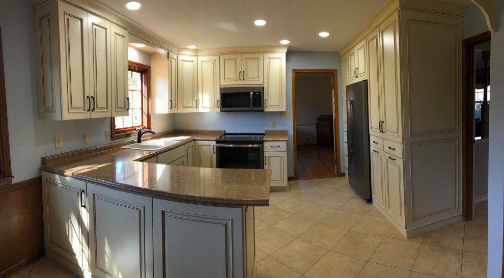 Mid-sized arts and crafts u-shaped eat-in kitchen in Indianapolis with a double-bowl sink, recessed-panel cabinets, light wood cabinets, laminate benchtops, stainless steel appliances, vinyl floors, brown floor and brown benchtop.