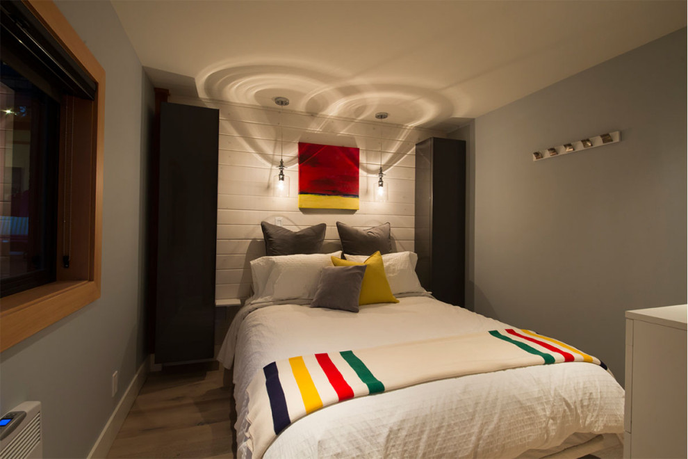 Стильный дизайн: гостевая спальня среднего размера, (комната для гостей) в морском стиле с серыми стенами, светлым паркетным полом, подвесным камином и стенами из вагонки - последний тренд