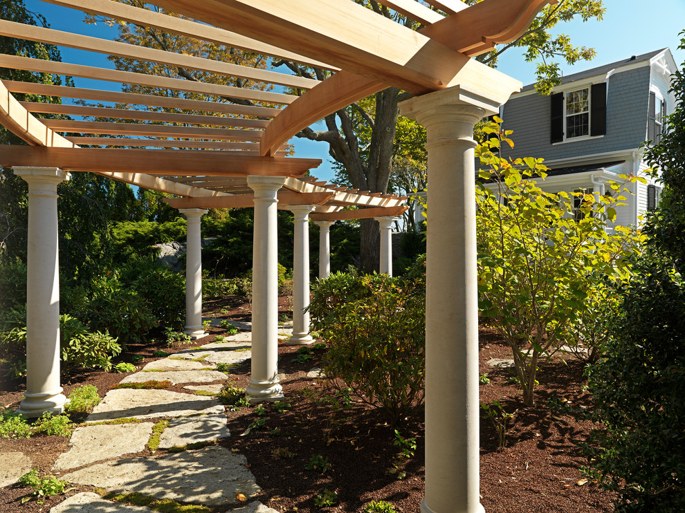 Design ideas for a traditional side yard patio in Boston with natural stone pavers and a pergola.