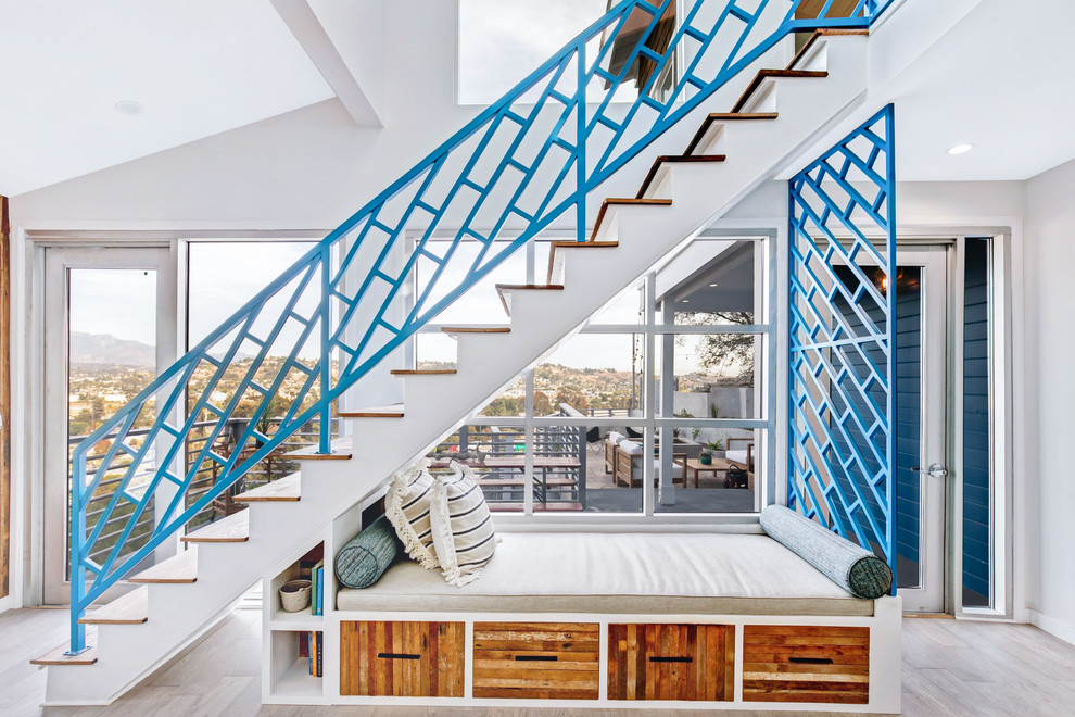 Inspiration for a beach style wood straight staircase in Los Angeles with painted wood risers and metal railing.