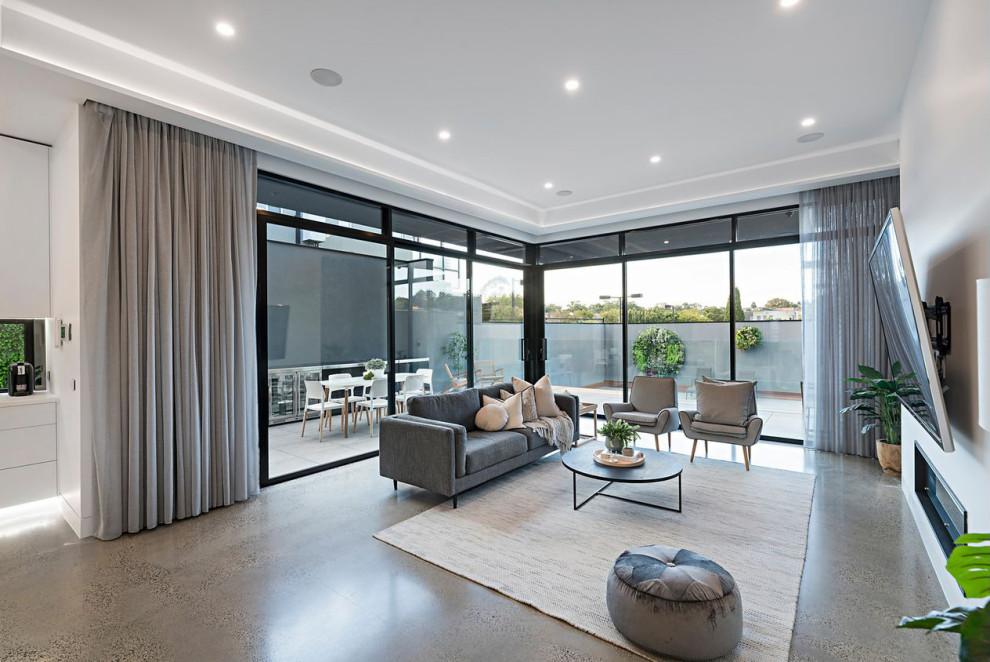 Large contemporary open concept living room in Melbourne with white walls, concrete floors, a ribbon fireplace, a plaster fireplace surround, a wall-mounted tv, grey floor and recessed.