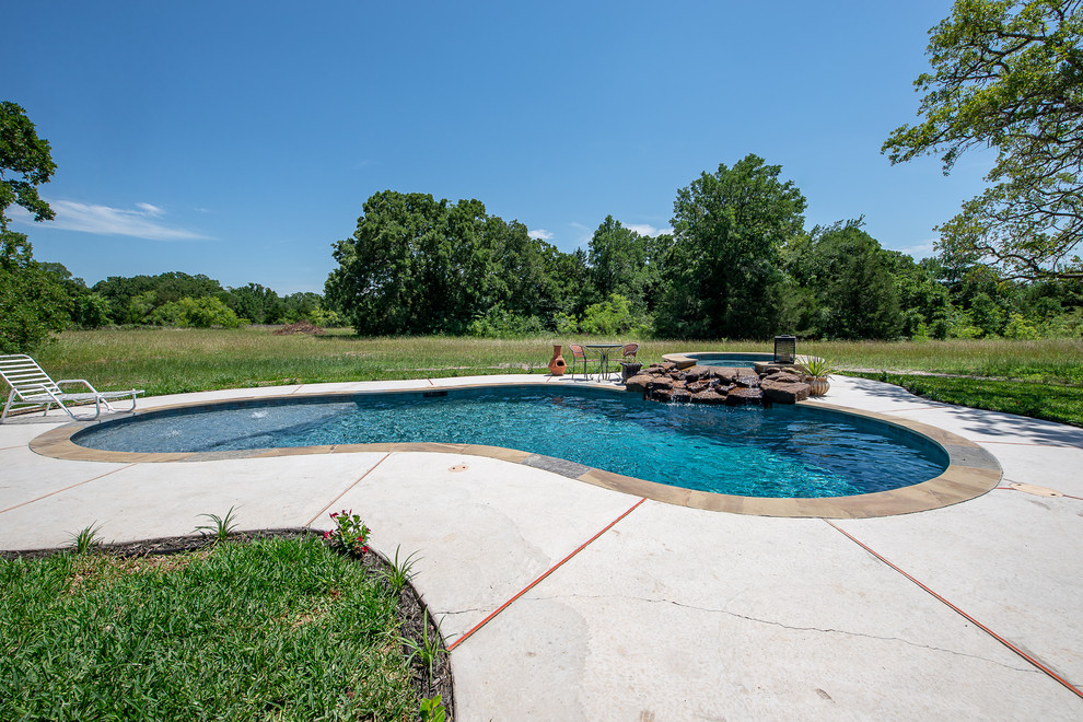 Design ideas for a mid-sized country backyard custom-shaped natural pool in Other with a hot tub and natural stone pavers.