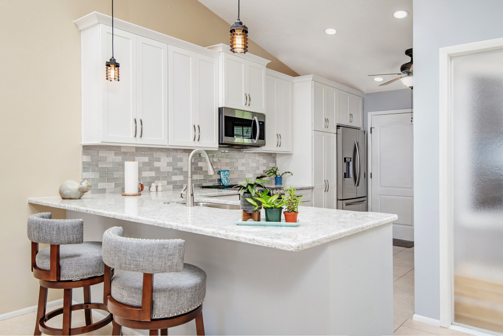 Design ideas for a mid-sized contemporary l-shaped separate kitchen in Tampa with an undermount sink, shaker cabinets, white cabinets, quartz benchtops, grey splashback, glass sheet splashback, stainless steel appliances, ceramic floors, a peninsula, beige floor, white benchtop and vaulted.