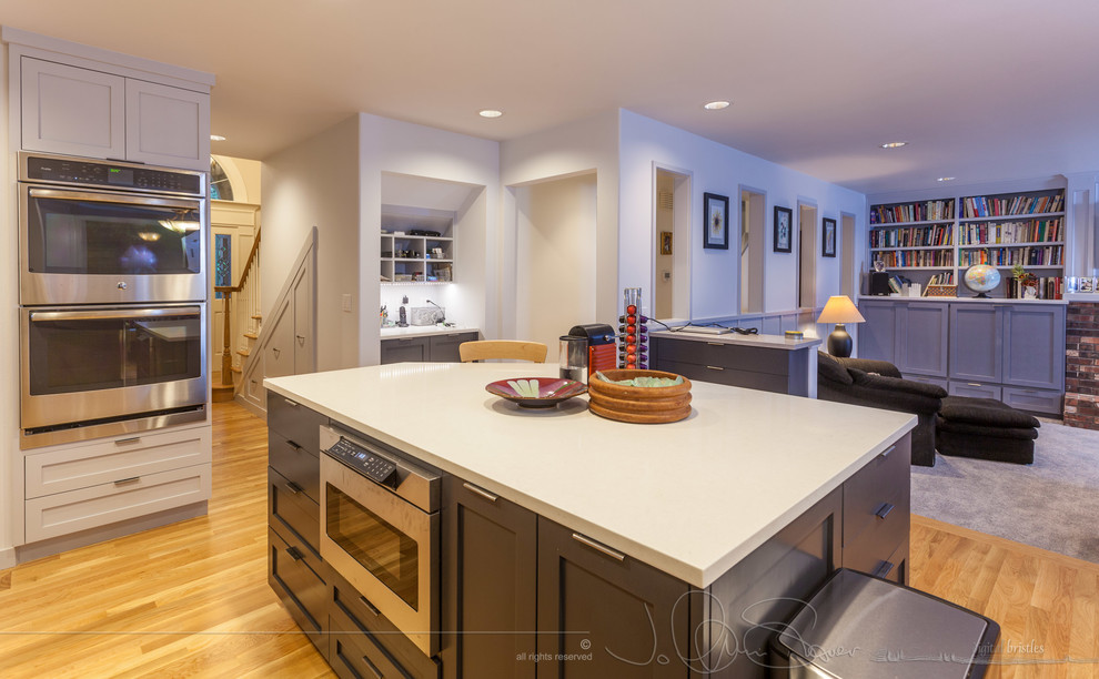 Enclosed kitchen - large transitional light wood floor enclosed kitchen idea in Seattle with a double-bowl sink, shaker cabinets, gray cabinets, quartz countertops, gray backsplash, glass sheet backsplash, stainless steel appliances and an island