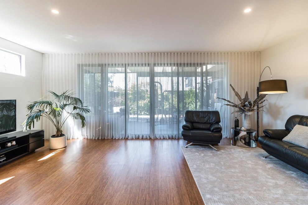 Medium sized contemporary kitchen/diner in Melbourne with a built-in sink, grey cabinets, engineered stone countertops, black appliances, bamboo flooring, an island, brown floors and white worktops.