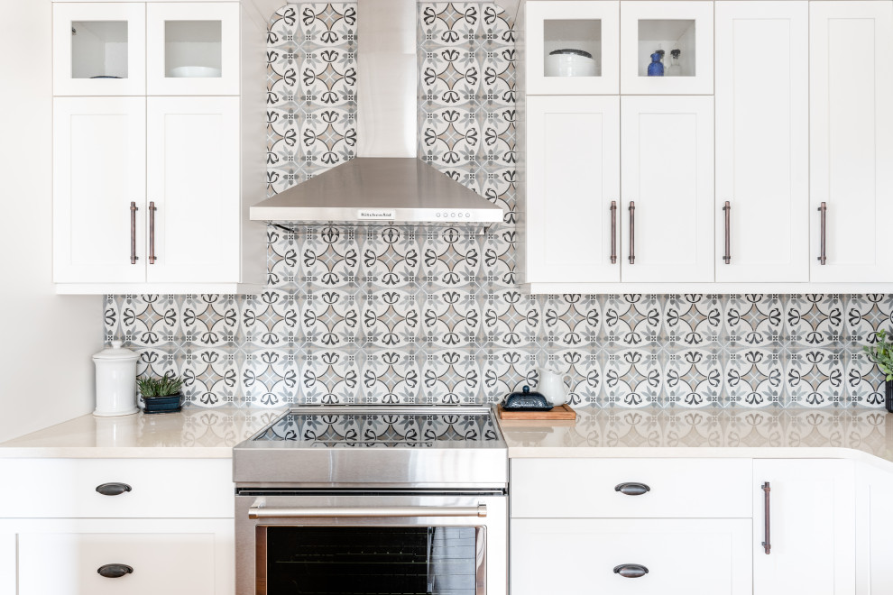 Mid-sized country l-shaped eat-in kitchen in Vancouver with an undermount sink, shaker cabinets, white cabinets, quartz benchtops, grey splashback, ceramic splashback, stainless steel appliances, medium hardwood floors, with island, brown floor and white benchtop.