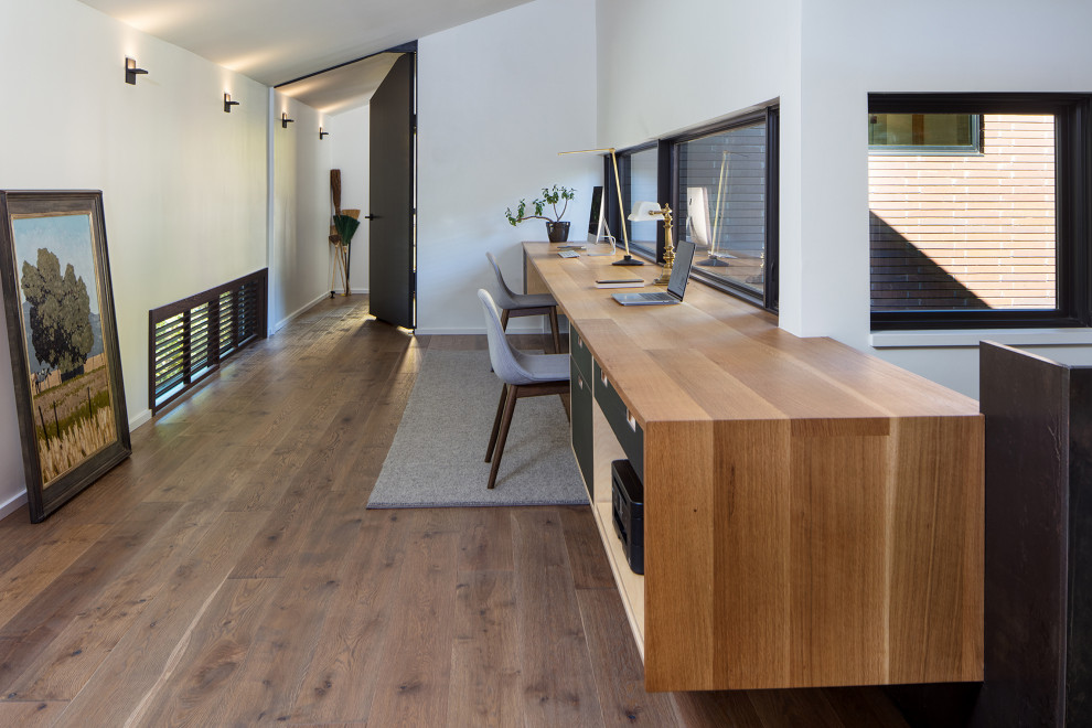 Inspiration pour un bureau design de taille moyenne avec un mur blanc, un sol en bois brun, un bureau intégré, un sol marron et un plafond voûté.