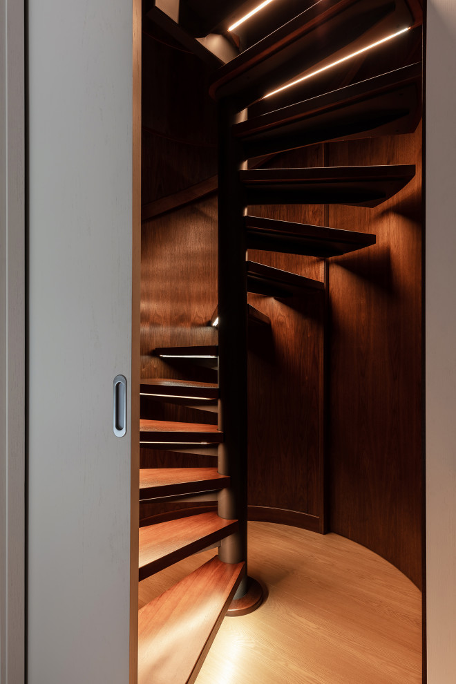 Идея дизайна: большая винтовая лестница в современном стиле с деревянными ступенями, деревянными перилами и панелями на стенах без подступенок