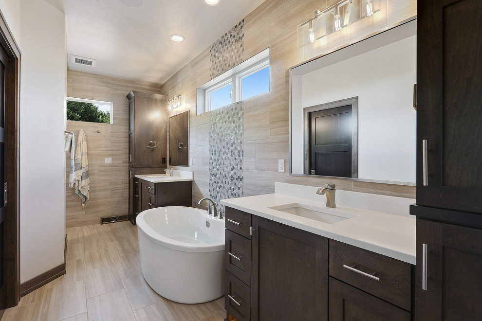 Inspiration for a mid-sized transitional master porcelain tile and beige tile porcelain tile and brown floor freestanding bathtub remodel with an undermount sink, quartzite countertops, white countertops, recessed-panel cabinets, dark wood cabinets, a two-piece toilet and beige walls