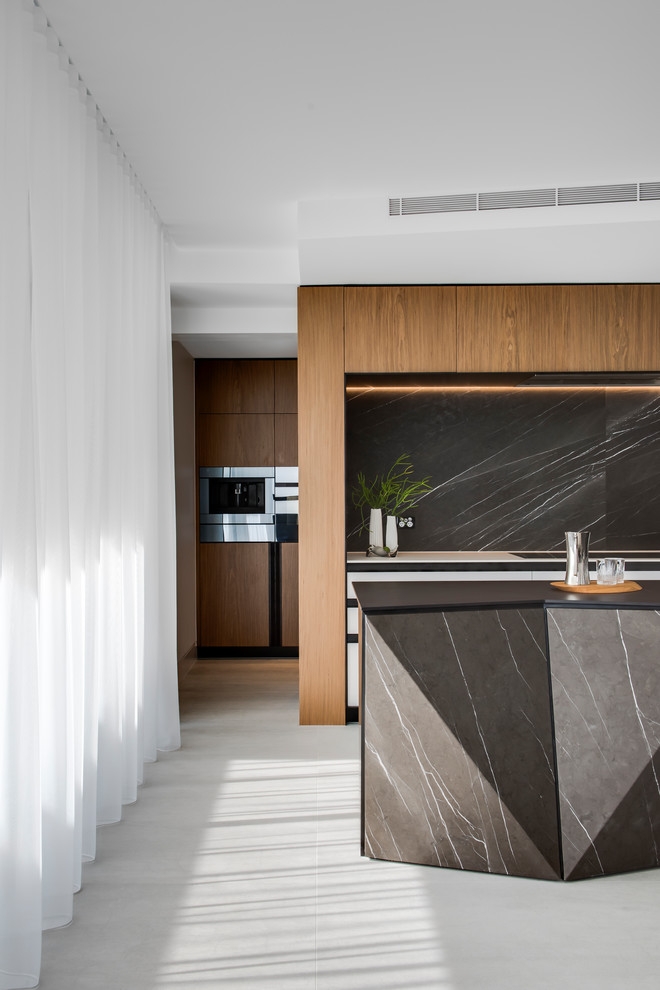 Photo of a large contemporary galley kitchen pantry in Sydney with a double-bowl sink, flat-panel cabinets, white cabinets, recycled glass benchtops, grey splashback, marble splashback, black appliances, porcelain floors, with island, grey floor and black benchtop.