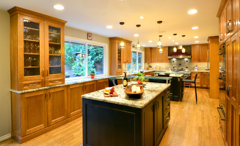 Photo of a large transitional u-shaped separate kitchen in Seattle with an undermount sink, recessed-panel cabinets, black cabinets, glass benchtops, multi-coloured splashback, ceramic splashback, coloured appliances, light hardwood floors, multiple islands and beige floor.