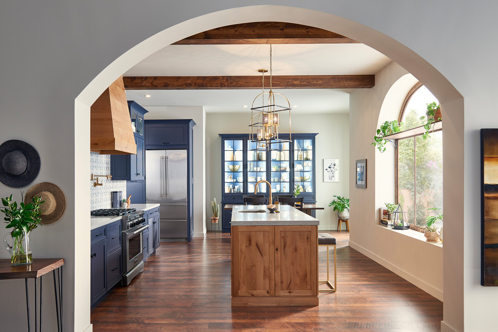 Large mediterranean single-wall eat-in kitchen in San Diego with an undermount sink, shaker cabinets, blue cabinets, solid surface benchtops, blue splashback, porcelain splashback, stainless steel appliances, with island, brown floor and grey benchtop.