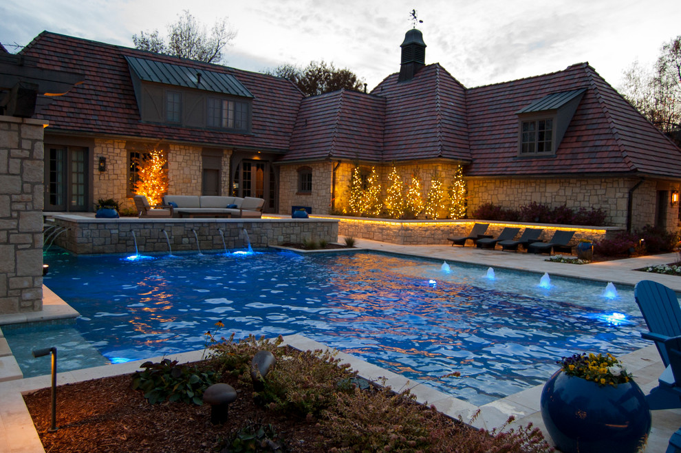 Photo of a large mediterranean backyard custom-shaped lap pool in Oklahoma City with a water feature and natural stone pavers.
