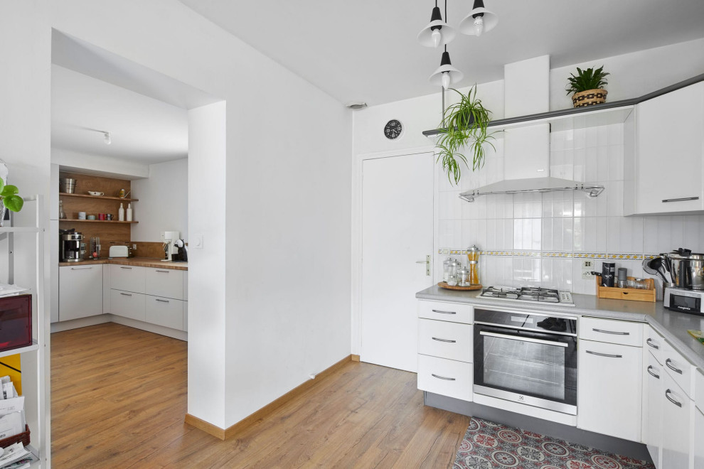Mid-sized contemporary l-shaped kitchen with a single-bowl sink, beaded inset cabinets, white cabinets, wood benchtops, white splashback, ceramic splashback, stainless steel appliances, laminate floors, with island, multi-coloured floor and green benchtop.