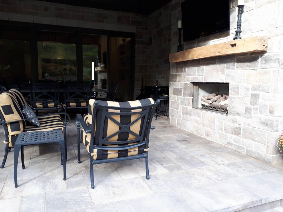 Example of a mid-sized transitional backyard concrete paver patio design with a fireplace and a roof extension