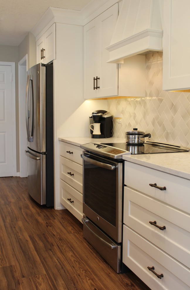 Example of a transitional kitchen design with recessed-panel cabinets, white cabinets, quartz countertops and an island