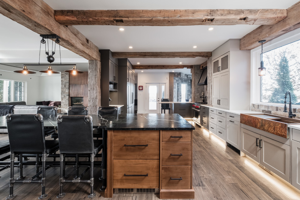Inspiration for a rustic l-shaped dark wood floor and brown floor kitchen remodel in Toronto with a farmhouse sink, shaker cabinets, gray cabinets, stainless steel appliances, an island and white countertops