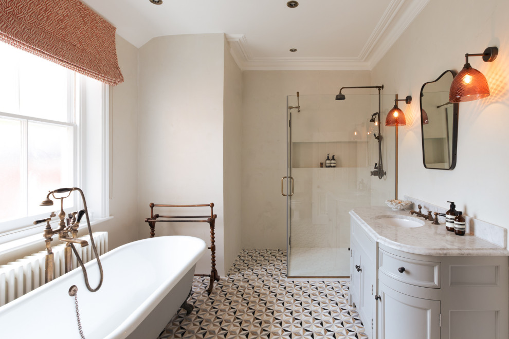 Источник вдохновения для домашнего уюта: большая главная, серо-белая ванная комната в стиле неоклассика (современная классика) с фасадами в стиле шейкер, серыми фасадами, отдельно стоящей ванной, открытым душем, унитазом-моноблоком, серыми стенами, мраморным полом, врезной раковиной, мраморной столешницей, разноцветным полом, душем с распашными дверями, белой столешницей, тумбой под одну раковину, напольной тумбой и кессонным потолком