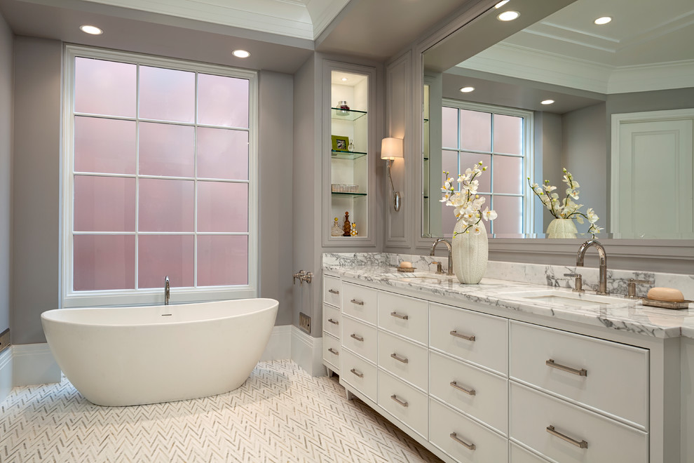 This is an example of a transitional master bathroom in Chicago with white cabinets, a freestanding tub, grey walls, an undermount sink and multi-coloured floor.