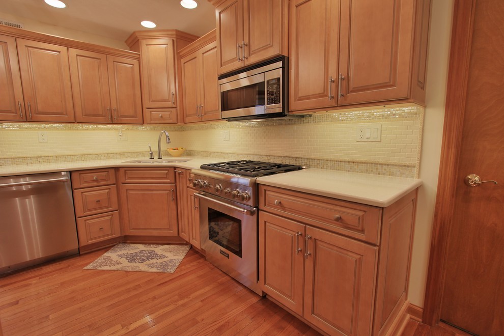 Inspiration for a mid-sized medium tone wood floor eat-in kitchen remodel with an undermount sink, medium tone wood cabinets, quartzite countertops, beige backsplash, ceramic backsplash and stainless steel appliances