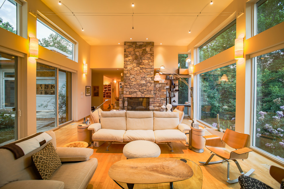 Photo of an expansive contemporary open concept living room in Raleigh with beige walls, light hardwood floors, a two-sided fireplace, a stone fireplace surround and a built-in media wall.