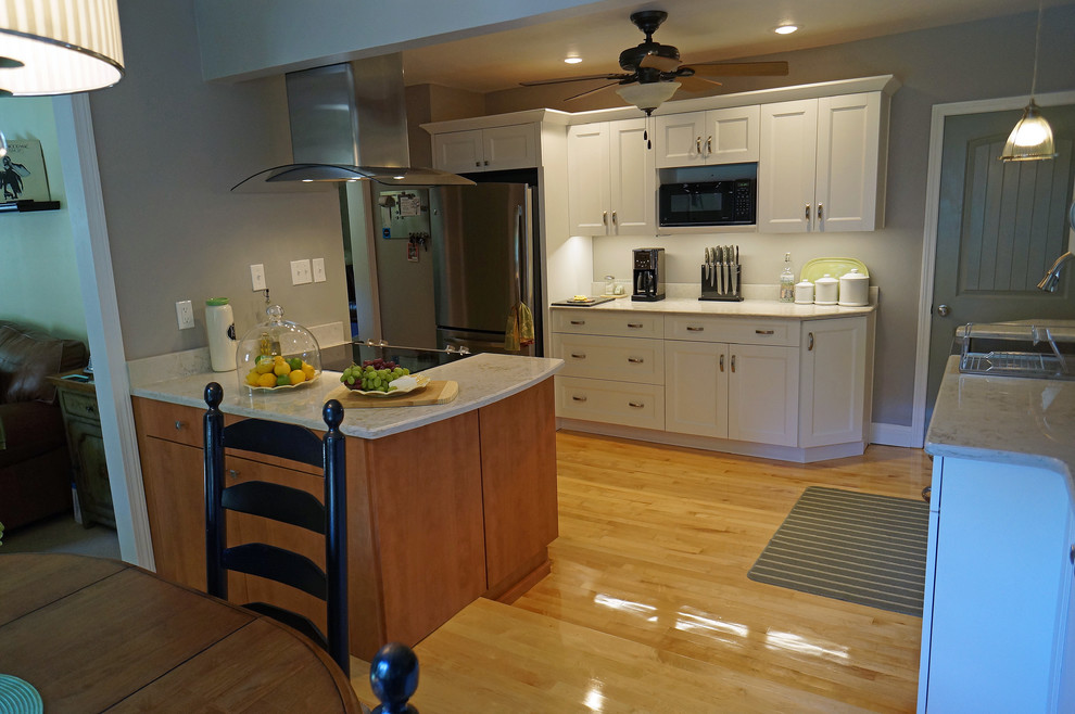 Large transitional l-shaped light wood floor eat-in kitchen photo in Boston with a farmhouse sink, shaker cabinets, white cabinets, quartz countertops, white backsplash, stone slab backsplash, stainless steel appliances and an island
