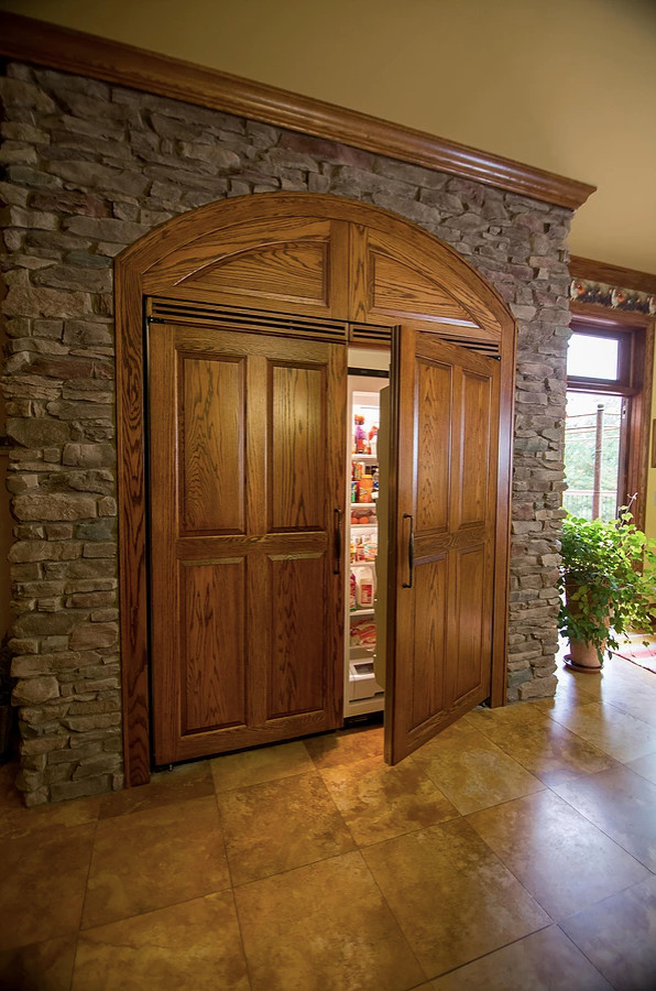 Inspiration for a large rustic u-shaped porcelain tile and beige floor eat-in kitchen remodel with an undermount sink, raised-panel cabinets, green cabinets, granite countertops, beige backsplash, porcelain backsplash, paneled appliances, an island and multicolored countertops
