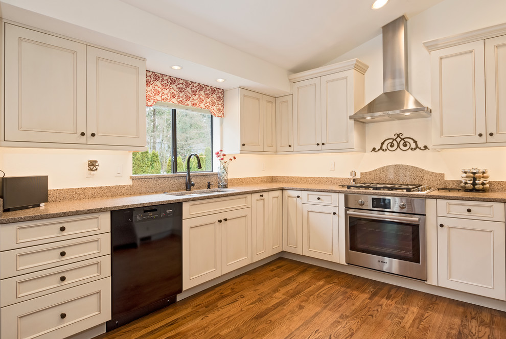 Inspiration for a mid-sized traditional kitchen in Seattle with a double-bowl sink, recessed-panel cabinets, white cabinets, granite benchtops, brown splashback, stone slab splashback, stainless steel appliances and medium hardwood floors.