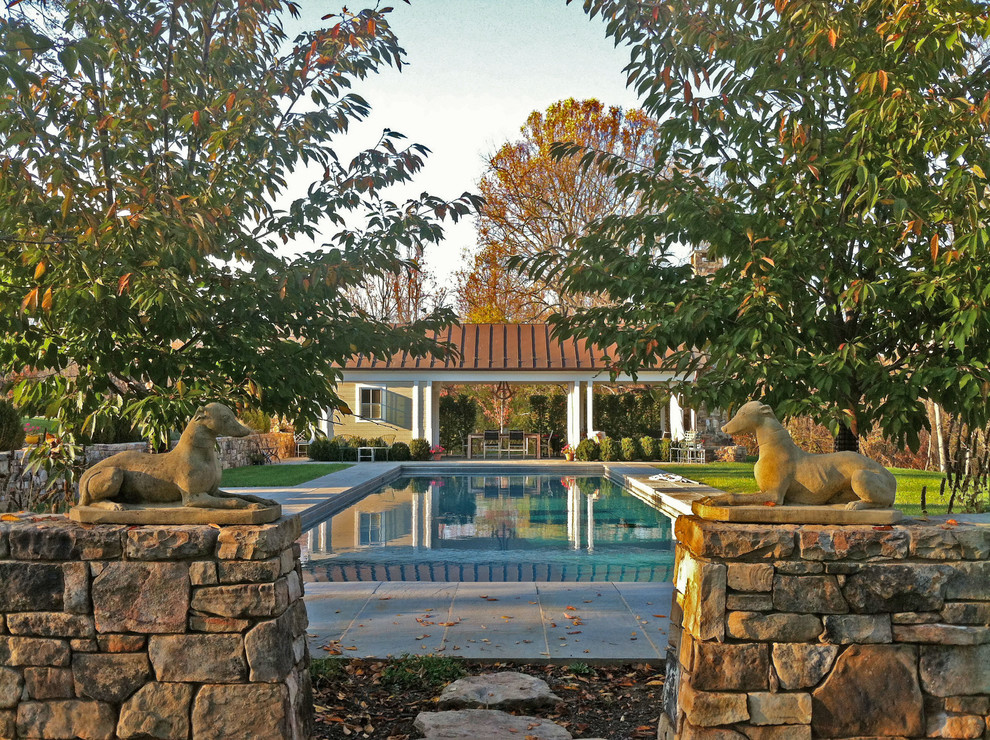 Large traditional backyard rectangular lap pool in Other with a pool house and tile.