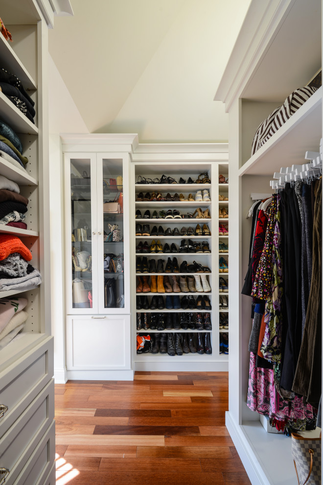 Traditional gender neutral walk-in wardrobe in Philadelphia with shaker cabinets, white cabinets, medium hardwood flooring, brown floors and a vaulted ceiling.