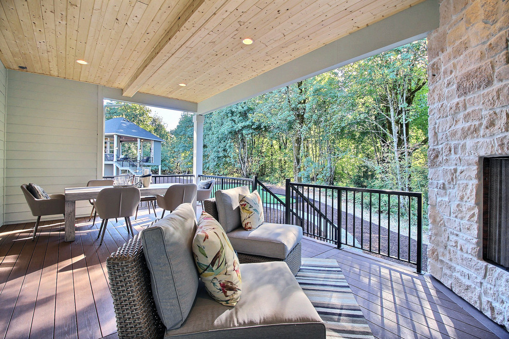 This is an example of an expansive arts and crafts backyard deck in Portland with an outdoor kitchen and a roof extension.