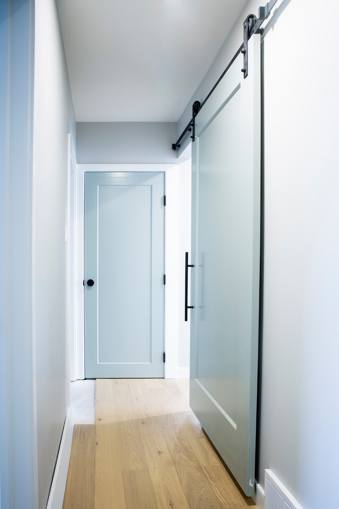 Photo of a mid-sized transitional hallway in Edmonton with grey walls, light hardwood floors and brown floor.